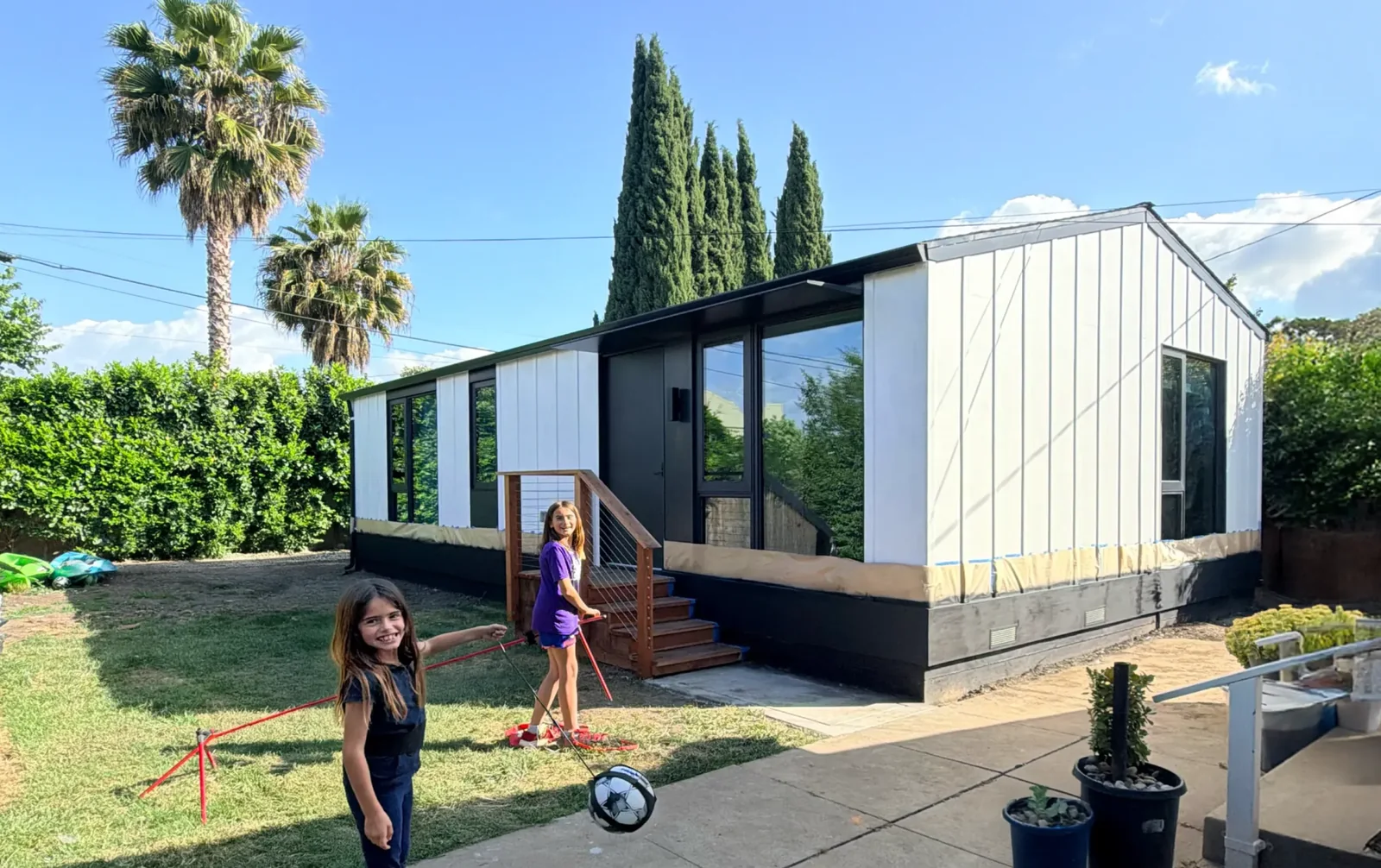 An installed LiveLarge home in a garden, with family members in the outdoor space